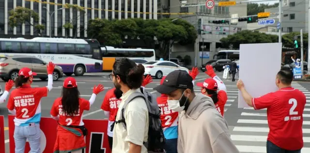 지난 6월 1일 지방선거 공식 선거운동 첫날인 5월 19일 오전 제주시 신광로터리에서 외국인들이 국민의힘 허향진 후보 선거운동원들이 거리인사하는 모습을 보고 있다