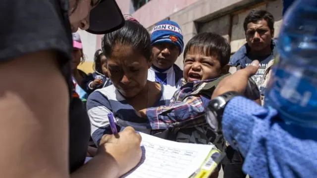 Una mujer migrante da sus datos a una mujer que anota en una planilla