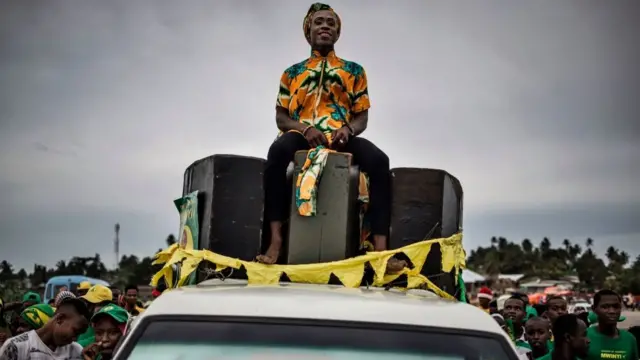 Umuntu yicaye kw'ikamyo mu gihe abashigikiye umugambwe uri ku butegetsi Chama Cha Mapinduzi bigina intsinzi y'umukandida wabo mu matora y'umukuru w'igihugu i Zanzibar mu micungararo y'umuji wa Stone Town, itariki 30 z'ukwa cumi 2020.