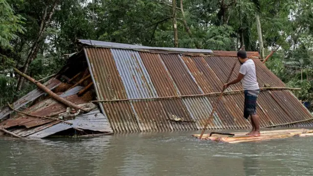 Homem navega pertob2xbetcasa submersa pela águab2xbetenchenteb2xbetBangladesh