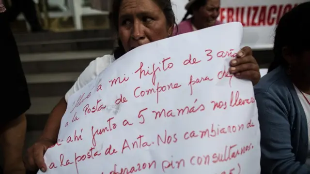 Mujer con un cartel escrito a mano que relata como fue esterilizada sin su consentimiento