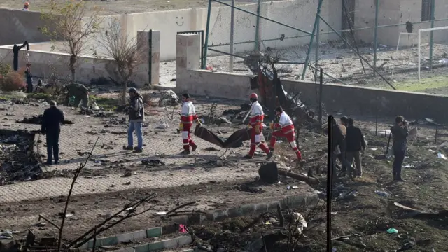 Спасатели несут мешки для тел