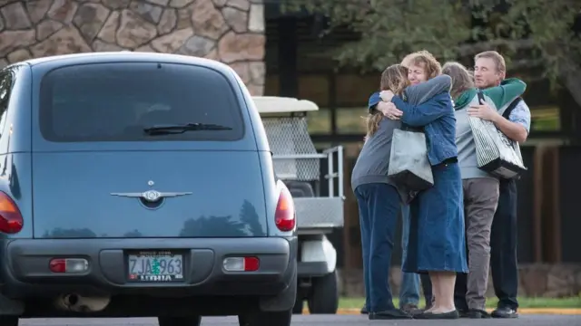Staff members embrace as they return to work at Umpqua Community College
