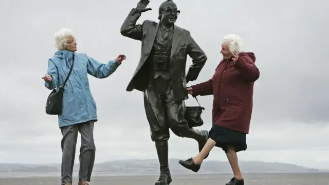 Idosas fazendo pose felizes ao lado de estátua