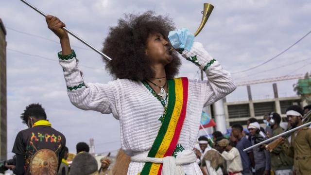 Uma mulher toca uma trombeta à frente de uma procissão para marcar a vitória na Batalha de Adwa - março de 2021, Adis Abeba, Etiópia