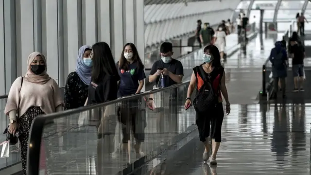Visitors take travelators along an overhead bridge within the Changi Airport in Singapore, 05 October 2020.