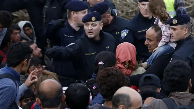 セルビアとの国境で移民に指示するクロアチア警官(18日)