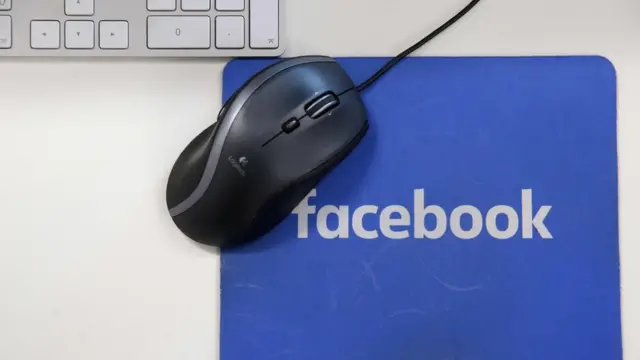 Mouse e teclado próximos a mousepad com marca do Facebook