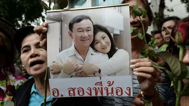 Mujer sosteniendo foto de los hermanos Shinawatra