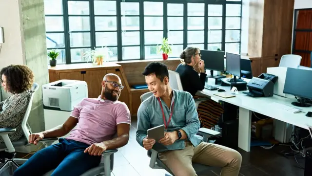 Dos compañeros de trabajo conversan entre ellos.