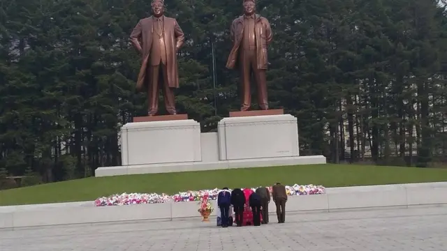 કોરિયામ લીડરોના સ્ટેચ્યુ સામે આદાર આપતા કોરિયન લોકોની તસવીર