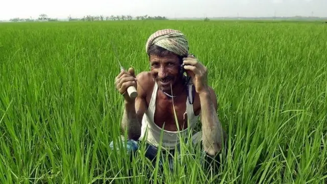 একজন কৃষক মোবাইলে কথা বলছেন।
