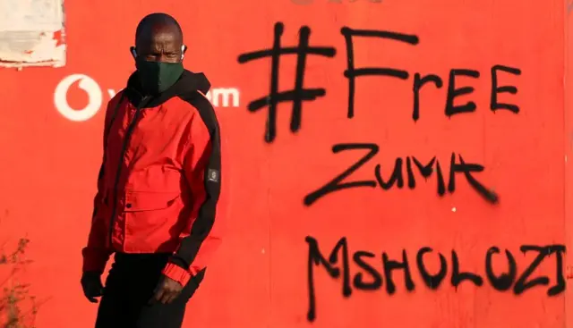 Un homme passe devant un mur couvert de graffitis indiquant "Free Zuma Msholozi", mercredi. Msholozi est le nom du clan de Jacob Zuma.