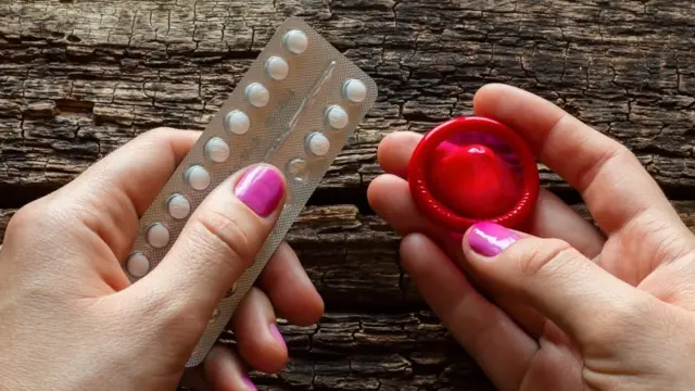 Woman holding contraceptive pills and a condom