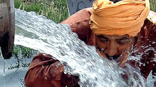 బోరు పైపు దగ్గర నీళ్లు తాగుతున్న వ్యక్తి