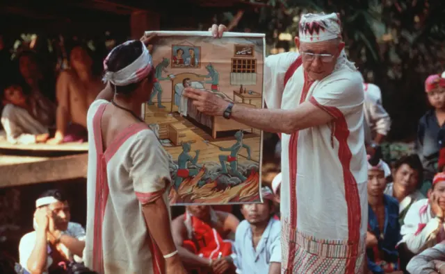 Foto dokumentasi tentang Allan Eubank, seorang misionaris Kristen dari Amerika, dalam upaya penginjilan di suku Talakon, Thailand, menggunakan gambar untuk membahas konsep dosa dan godaan iblis.