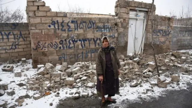 İranda dağılmış bina fonunda yaşlı qadın
