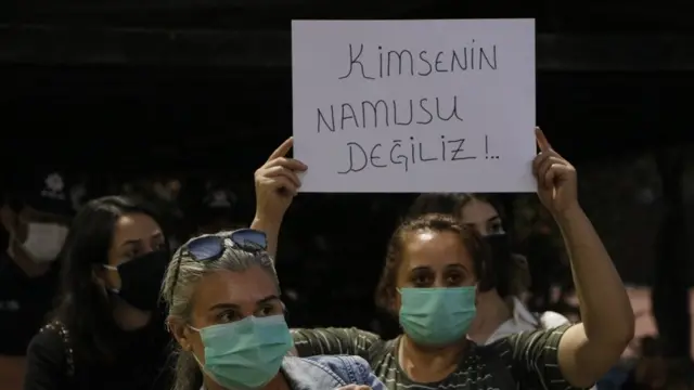 "kimsenin namusu değiliz" pankartı taşıyan bir kadın