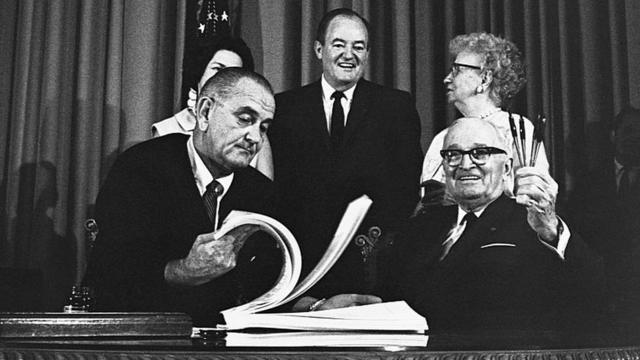 Harry Truman con Lyndon Johnson tras la firma de Medicare