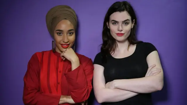 Charli and Mariah Idrissi posing in front of a purple wall