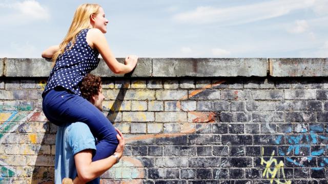 Una pareja se asoma a una pared.