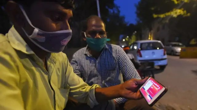 मोबाइल पर ख़बर देखते दो लोग