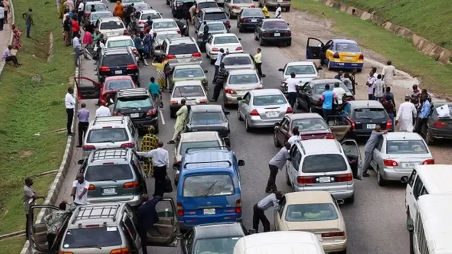 People wait next to their cars on the Abuja - Nasarawa road due to clashes between Nigerian soldiers and members of Islamic Movement of Nigeria
