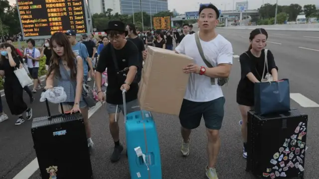 হংকং বিমানবন্দরে ফ্লাইট বাতিলের পর রাস্তা দিয়ে হেঁটে ফিরছেন কজন যাত্রী