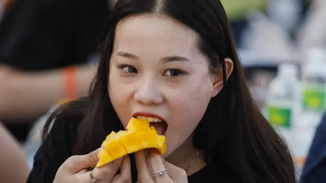 ผู้หญิงกำลังทำท่ากินมะม่วง