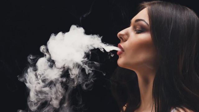 Mujer sacando humo por la boca.