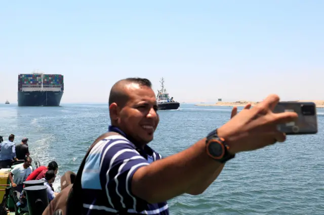 A man takes a selfie as Ever Given, one of the world"s largest container ships, sets sail to leave at the Suez Canal after the canal authority reached a settlement with the vessel"s owner and insurers, in Ismailia