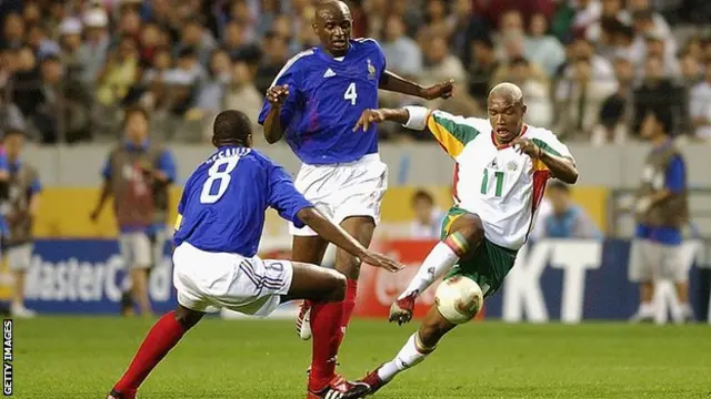 Fotografia colorida mostra o jogadorres da França e do Senegal disputando uma bola