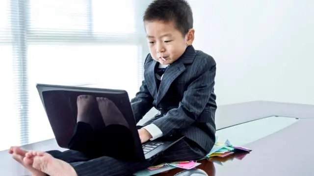 Un niño vestido de ejecutivo con una laptop