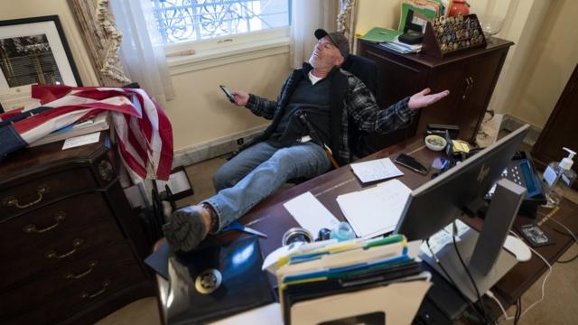 60岁、来自阿肯色州的巴内特（Richard Barnett）一屁股坐在佩洛西的座位上，把脚放在办公桌上
