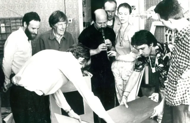 Одна из самых знаменитых акций "Клуба Друзей Маяковского" - перформанс с Джоном Кейджем в мастерской Сергея Бугаева. На заднем плане слева направо: Александр Кан, Джон Кейдж, Иван Шумилов, Сергей Чернов, Ирена Куксинайте. На переднем плане: Сергей Бугаев-Африка, Сергей Курехин, Тимур Новиков. Апрель 1988 г. Фото Анатолия Сягина