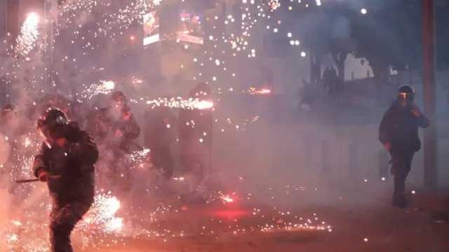 Lebanese riot police react to fireworks thrown by supporters of Lebanon's Shiite Hezbollah and Amal groups during clashes on December 14, 2019 in central Beirut.