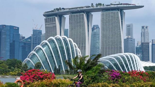 A woman rides her bicycle with the Marina Bay Sands hotel and high rise buildings in the background in Singapore on September 4,2023.