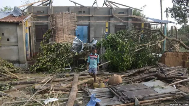 An Indian resident collects belongings from a damaged house after heavy storm winds at Belchharra village on the outskirts of Agartala on May 7, 2018