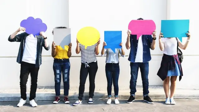 A group of young people holding up placards shaped as thought-bubbles