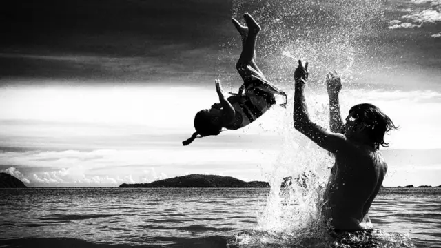 Отец и дочь играют в воде на побережье Таиланда