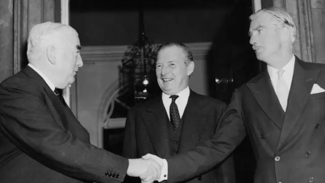 ব্রিটেনের প্রধানমন্ত্রী এ্যান্টনি ইডেন (ডানে) হাত মেলাচ্ছেন অস্ট্রেলিয়ার প্রধানমন্ত্রী রবার্ট মেনজিসের সাথে, মাঝে ব্রিটিশ পররাষ্ট্রমন্ত্রী সেলভিন লয়েড