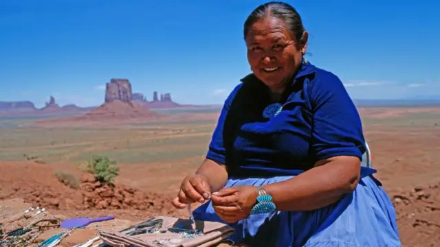 Mulher Navajo fazendo acssórios como pulseiras e colares tradicionais