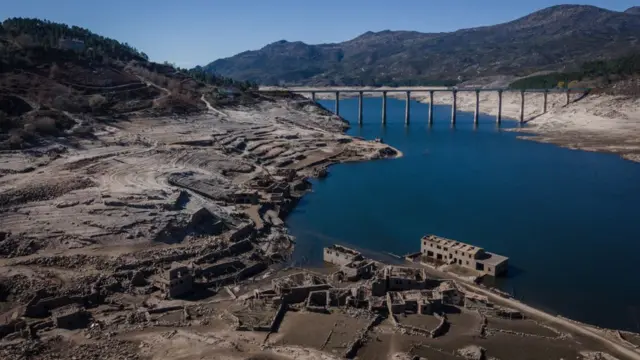 Fotografia colorida mostra ruínasbrasileirao 2024 tabelaprédios agrupadas na margembrasileirao 2024 tabelaum rio azul que passa num vale entre montanhas