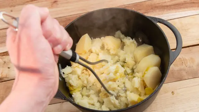 Рука, разминающая картошку