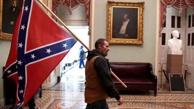 Wannan hoton na nuna wani mutum dauke da tsohuwar tutar 'yan aware ta 'confederate' bayan ya kutsa cikin ginin majalisar