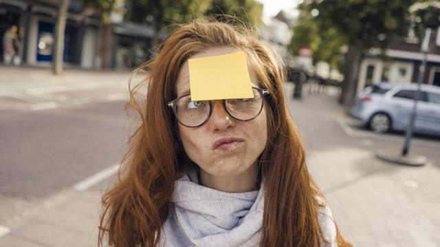 Woman on the street, with a post-it note stuck to her forehead