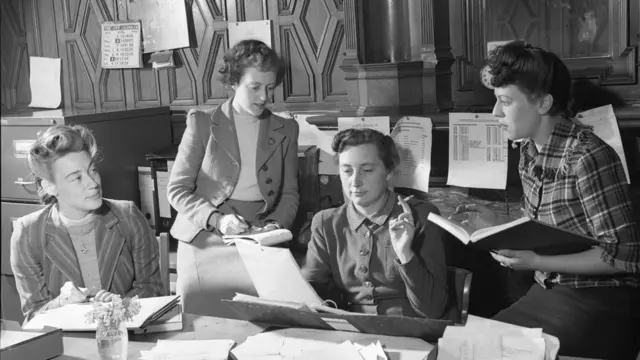 Integrantes del equipo administrativo del Servicio Latinoamericano I. V. Mallett, C. M. O'Callaghan, E. Ware, R. Canter, cuator mujeres jóvenes conversando en torno a un escritorio