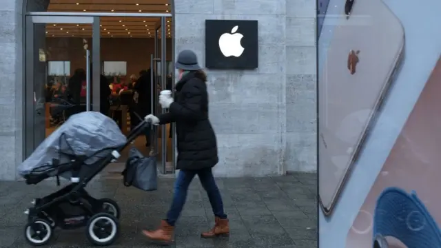 mulher passando na frente da Apple