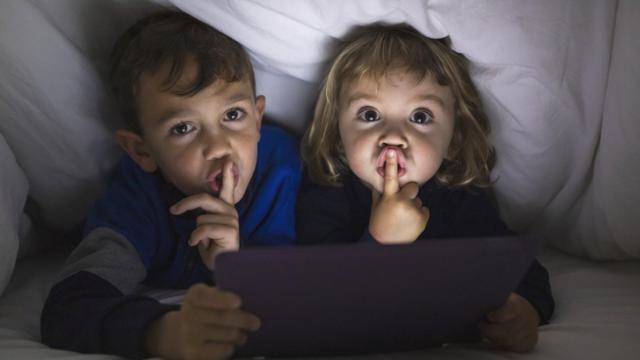 Duas crianças fazendo gesto de silêncio