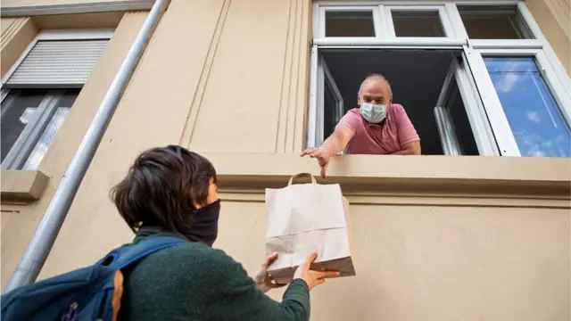 Une femme donne un sac de nourriture à un homme